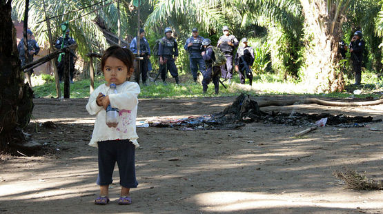 kleines Mädchen steht verängstigt vor einer Gruppe Paramilitärs